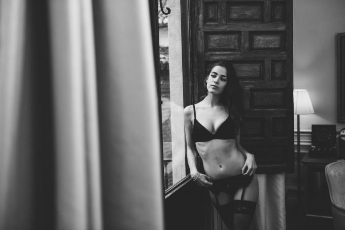 אישה צעירה סקסית פוזות הלבשה תחתונה ליד חלון