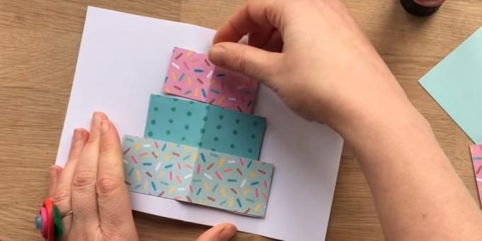 חותכים את מלבן משלוש שכבות נייר צבעוני בגודל העתיד של עוגה